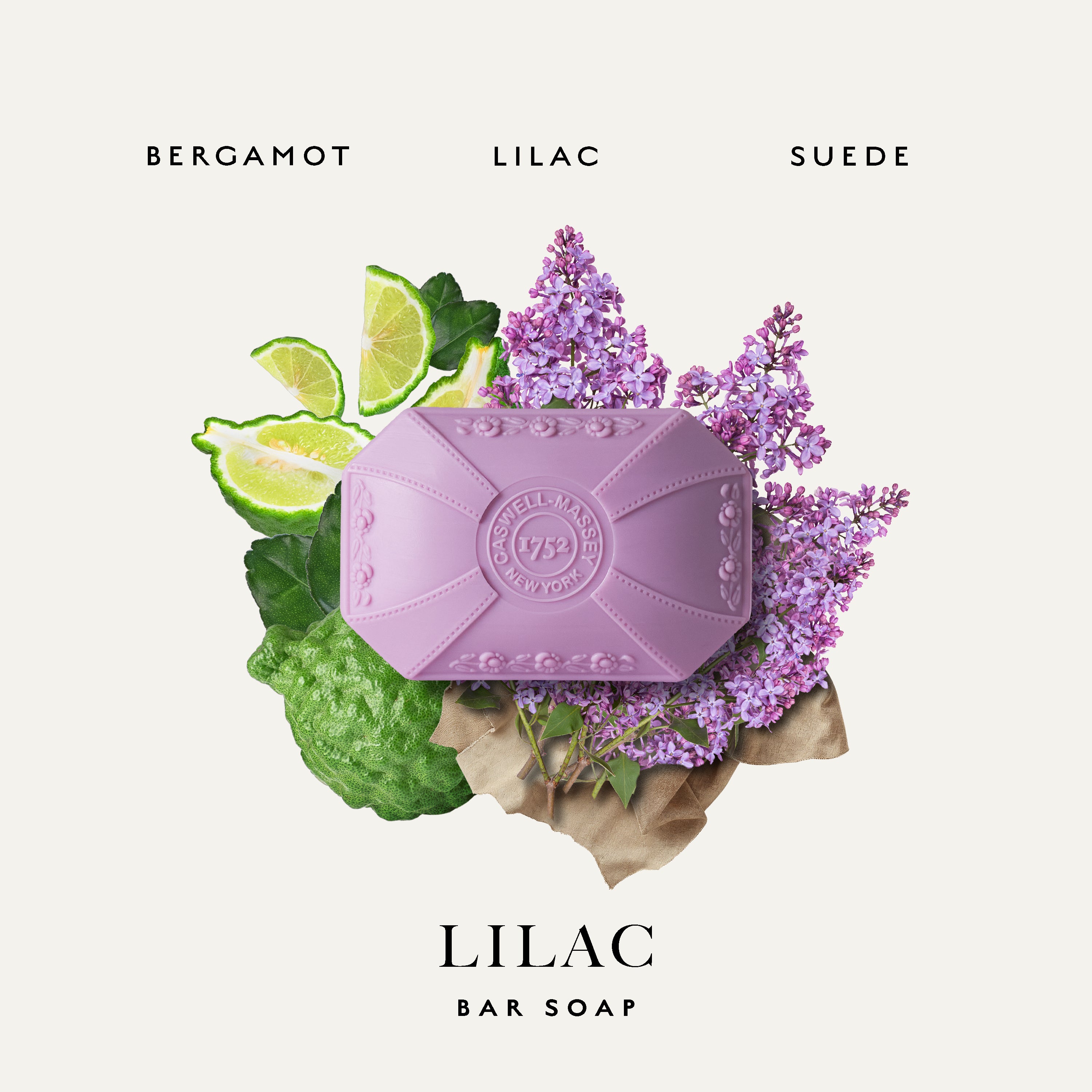 A lavender colored bar of Caswell-Massey Lilac soap centered on a light cream background, surrounded by botanical and citrus props including lilac flowers, green leaves, lime slices, and a brown paper accent. Text above reads BERGAMOT LILAC SUEDE and below reads LILAC BAR SOAP.
