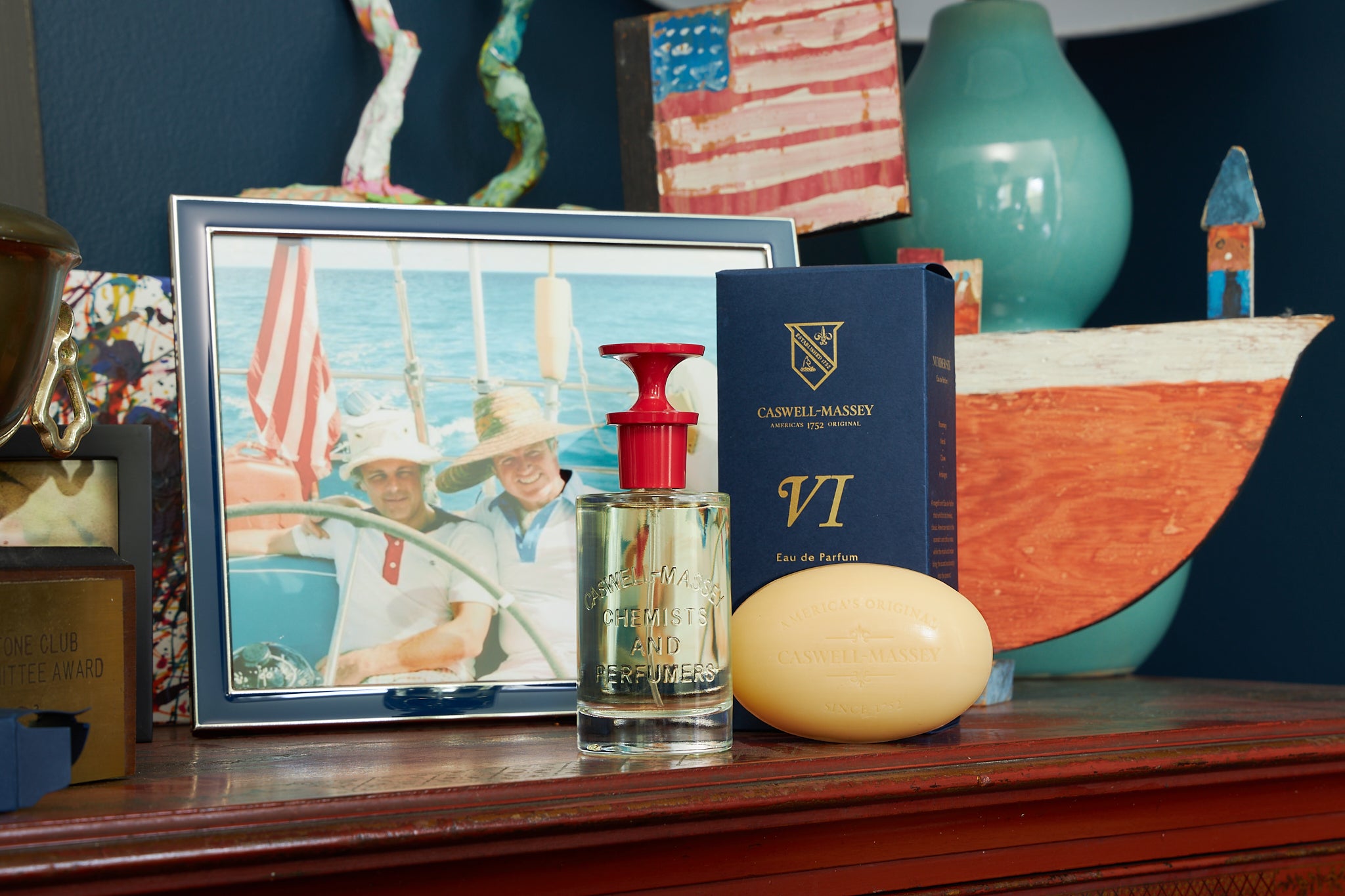 Caswell-Massey Number Six Eau de Parfum and Number Six Bar Soap shown on wood bureau with picture frame of dad and son with nautical decor behind it