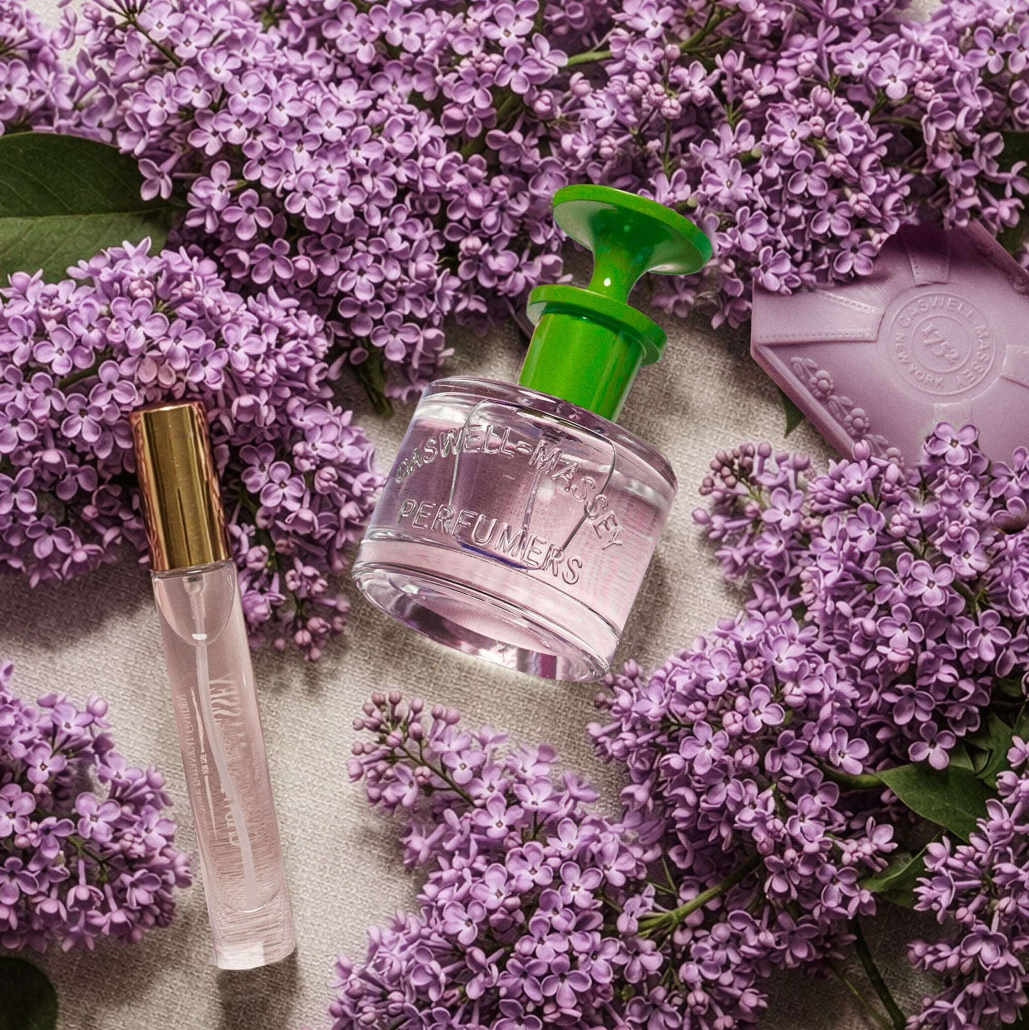 Caswell-Massey Lilac Eau de Toilette shown surround by fresh lilacs. Image shows the Lilac Eau de Toilette 60 ml, Lilac Eau de Toilette 7.5 ml, and the Lilac Bath Soap 3.5oz