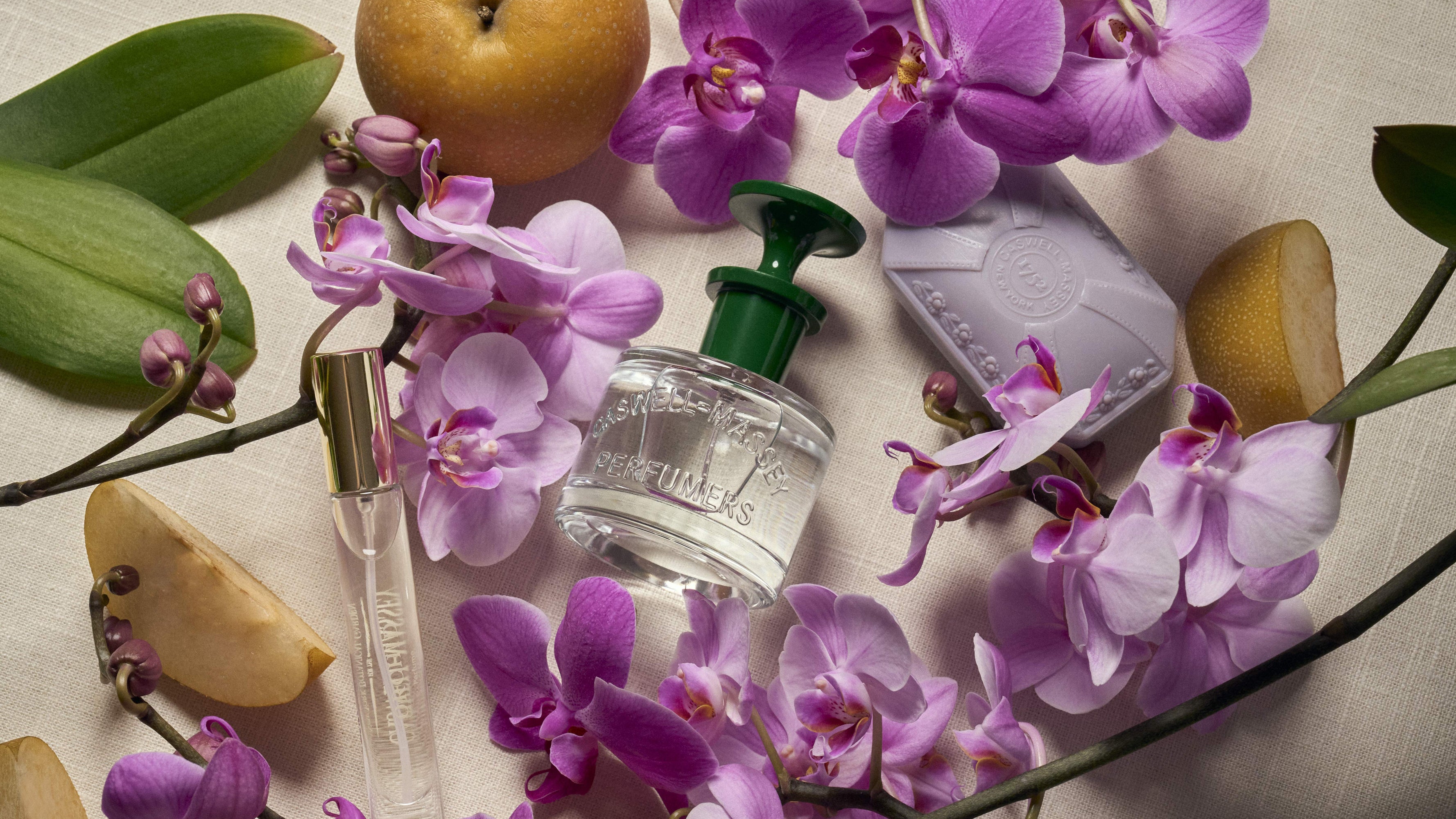 Orchid Perfume and purple Orchid Bar Soap with purple orchids and green leaves on a light background
