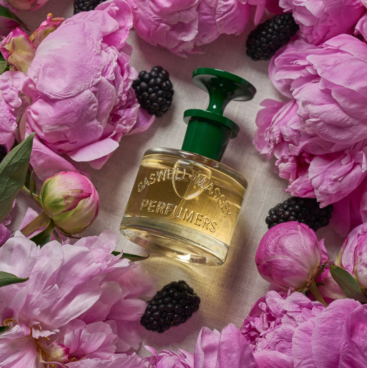 Caswell-Massey Peony Perfume. Bottle shown surrounded by fresh pink peonies and fresh blackberries.