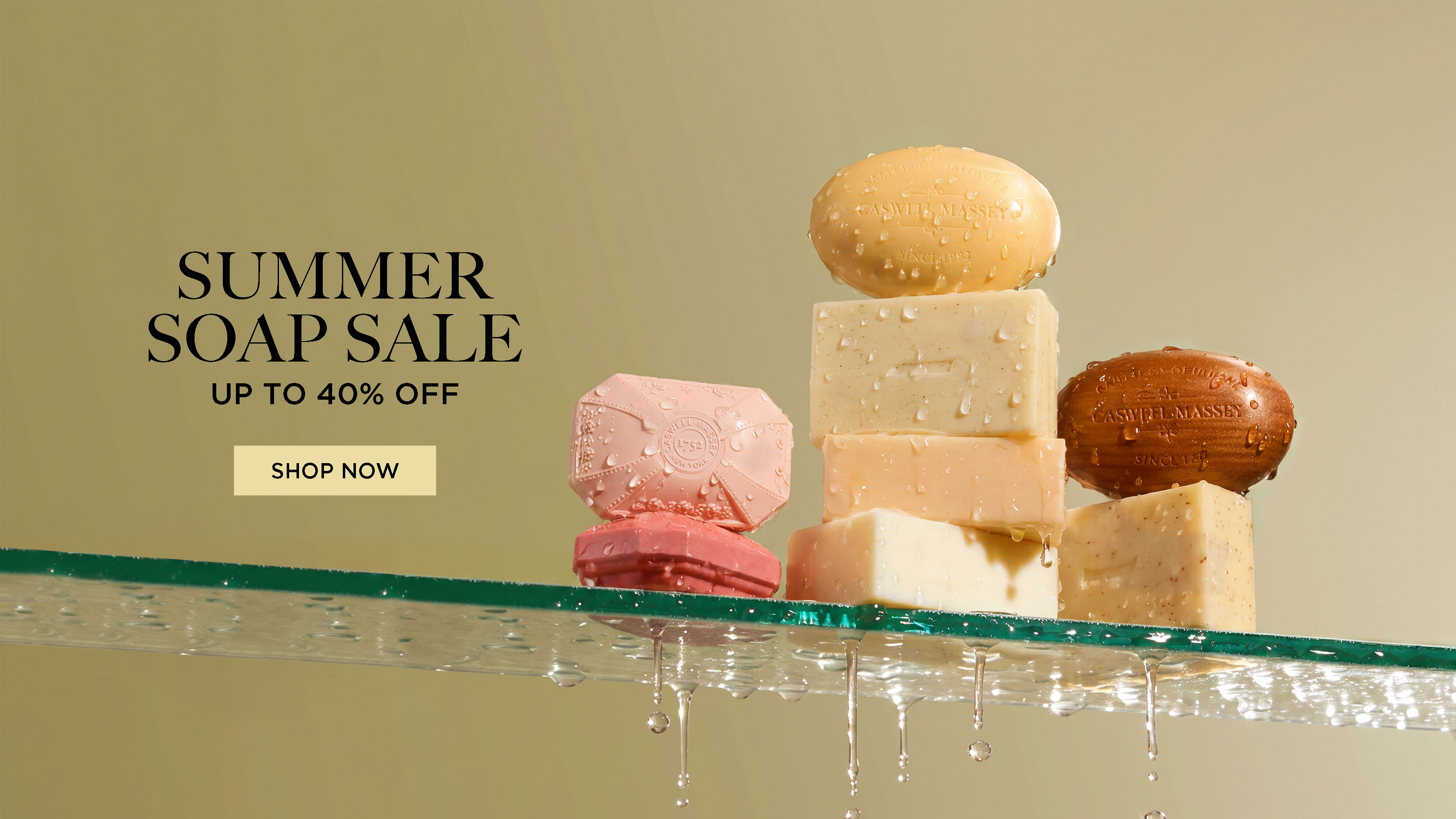 Caswell-Massey's Summer Soap Sale 2026: Take 20% off Single Soaps with Code: SOAP2026. Image shows bars of soap stacked together on a shelf in a shower.