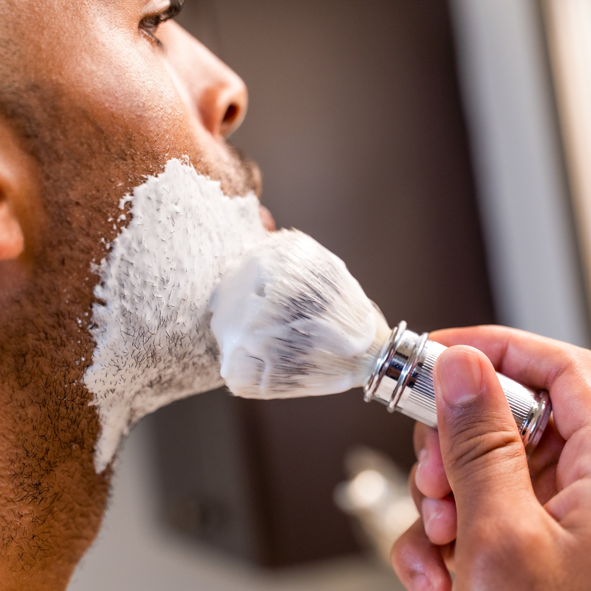 Close-up of man applying Caswell-Massey Almond Shave Cream to his face with Caswell-Massey Ribbed Chrome Shave Brush