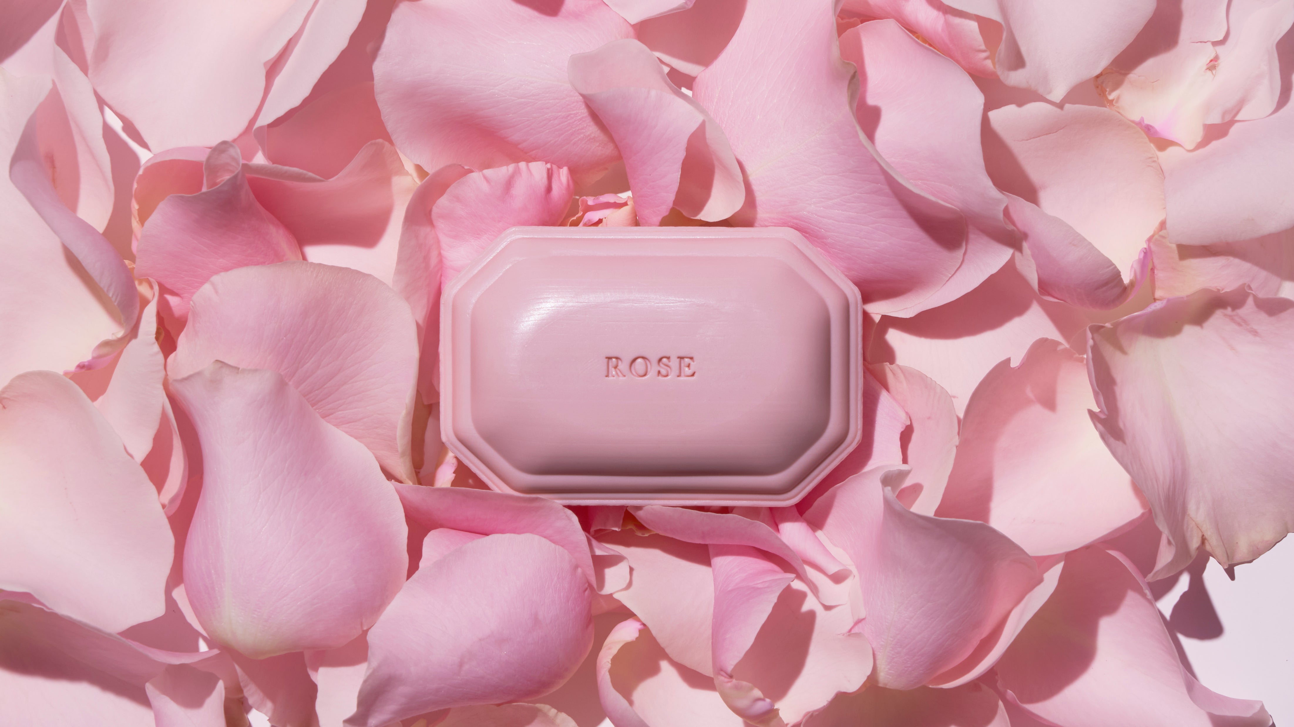Caswell-Massey Rose Bar Soap: pastel pink soap in art deco form shown with soft pink rose petals