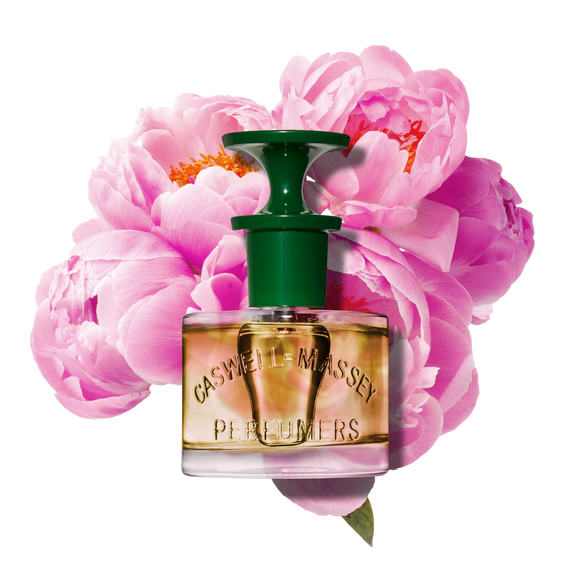 Caswell-Massey Peony Perfume for Women. Image shows perfume bottle against blooming pink peonies