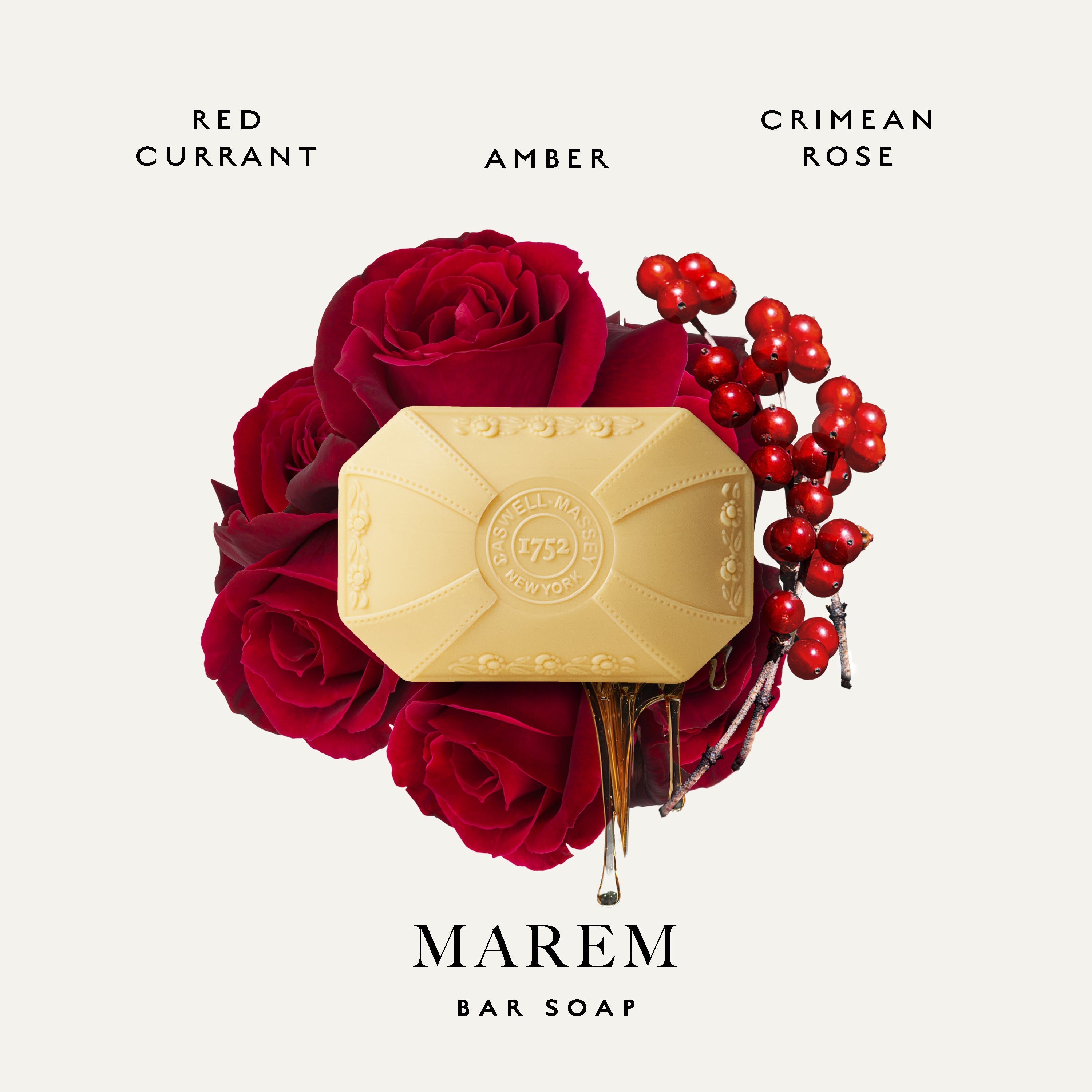 A bar of Marem Bar Soap in a pale yellow hexagonal wrapper, nestled in a bouquet of deep red roses and red berries, with scent names 'RED CURRANT', 'AMBER', and 'CRIMEAN ROSE' on a light beige background.
