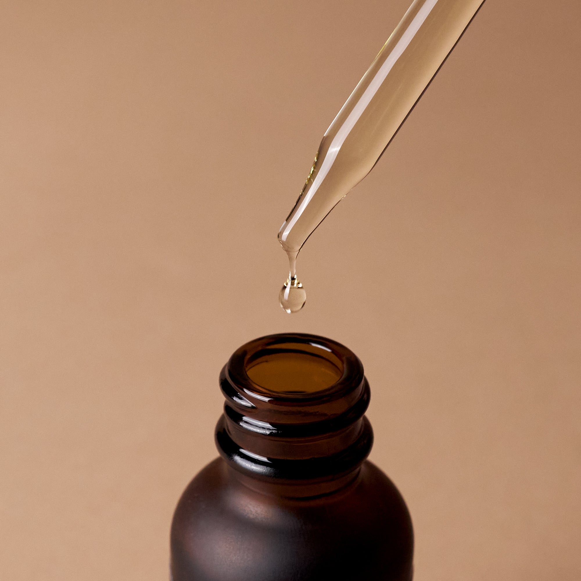Caswell-Massey Heritage Face & Beard Oil: close-up shot of oil dripping out of dropper into amber bottle