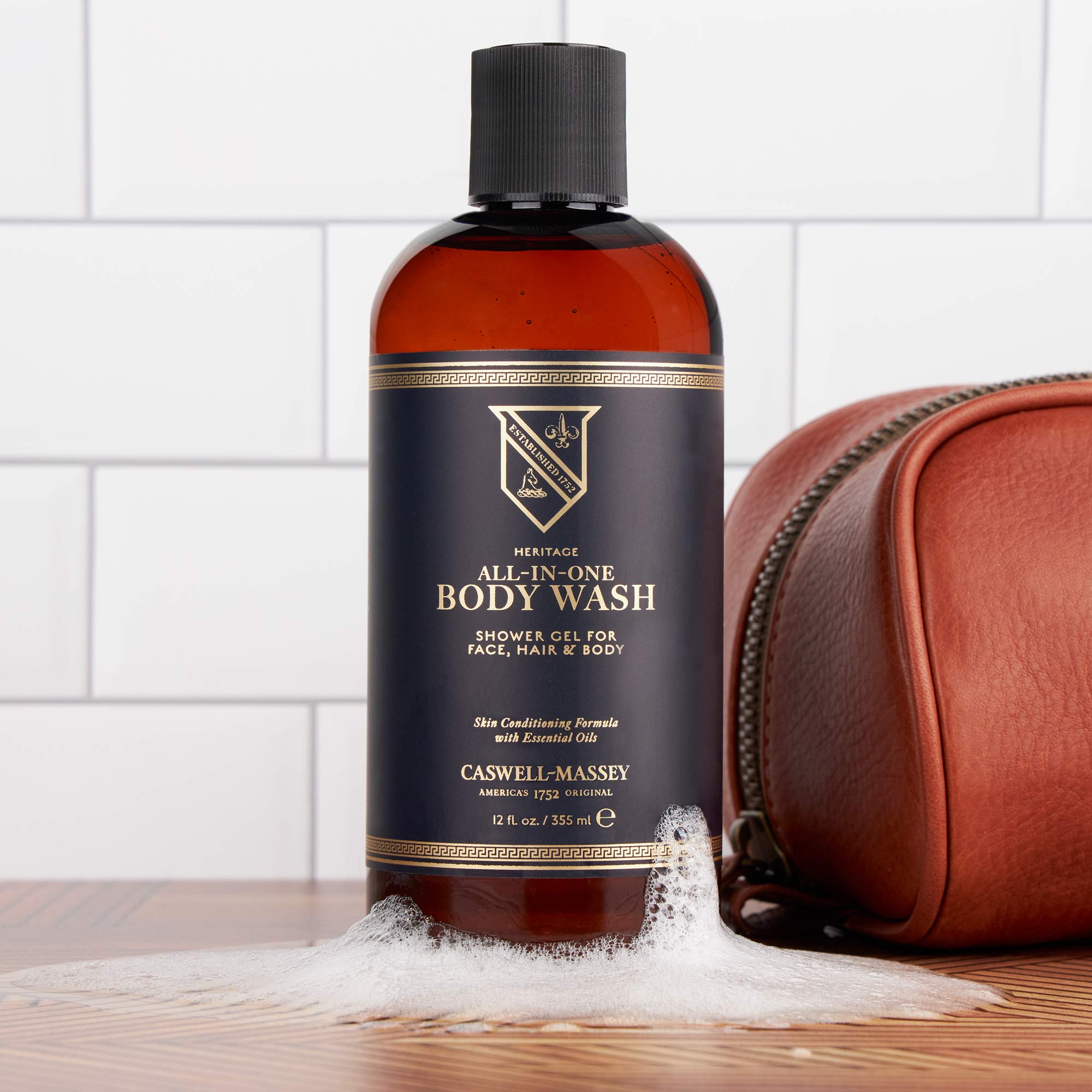 Caswell-Massey All-in-One Body Wash, image shows 12oz All-in-One on bathroom counter next to leather dopp kit.