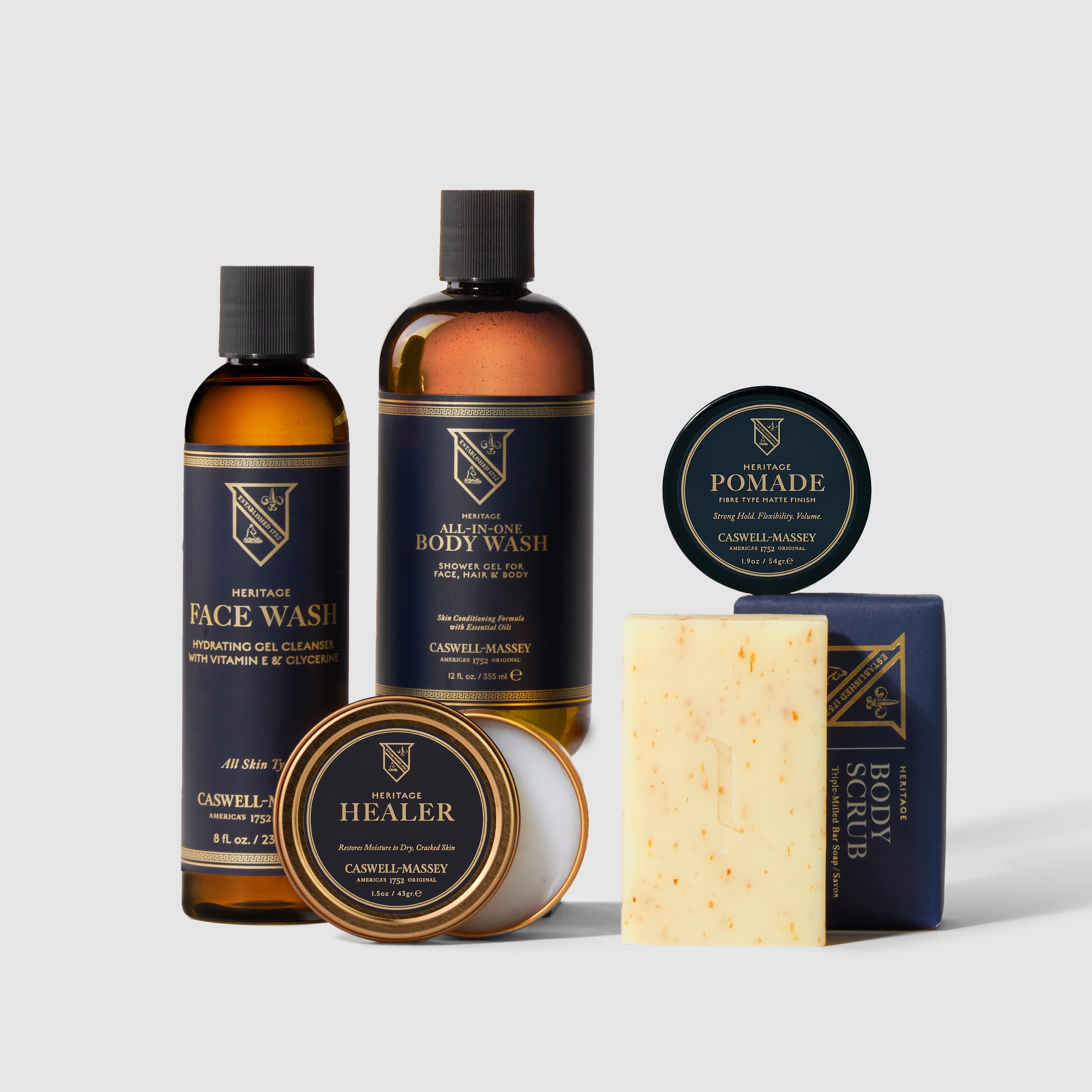 Men's Caswell-Massey Heritage Grooming Gift Set: Body Scrub Soap, Healer Hand Salve, Medium Fiber Hair Pomade, Face Wash, and All-in-One Body Wash included in navy gift box with red ribbon