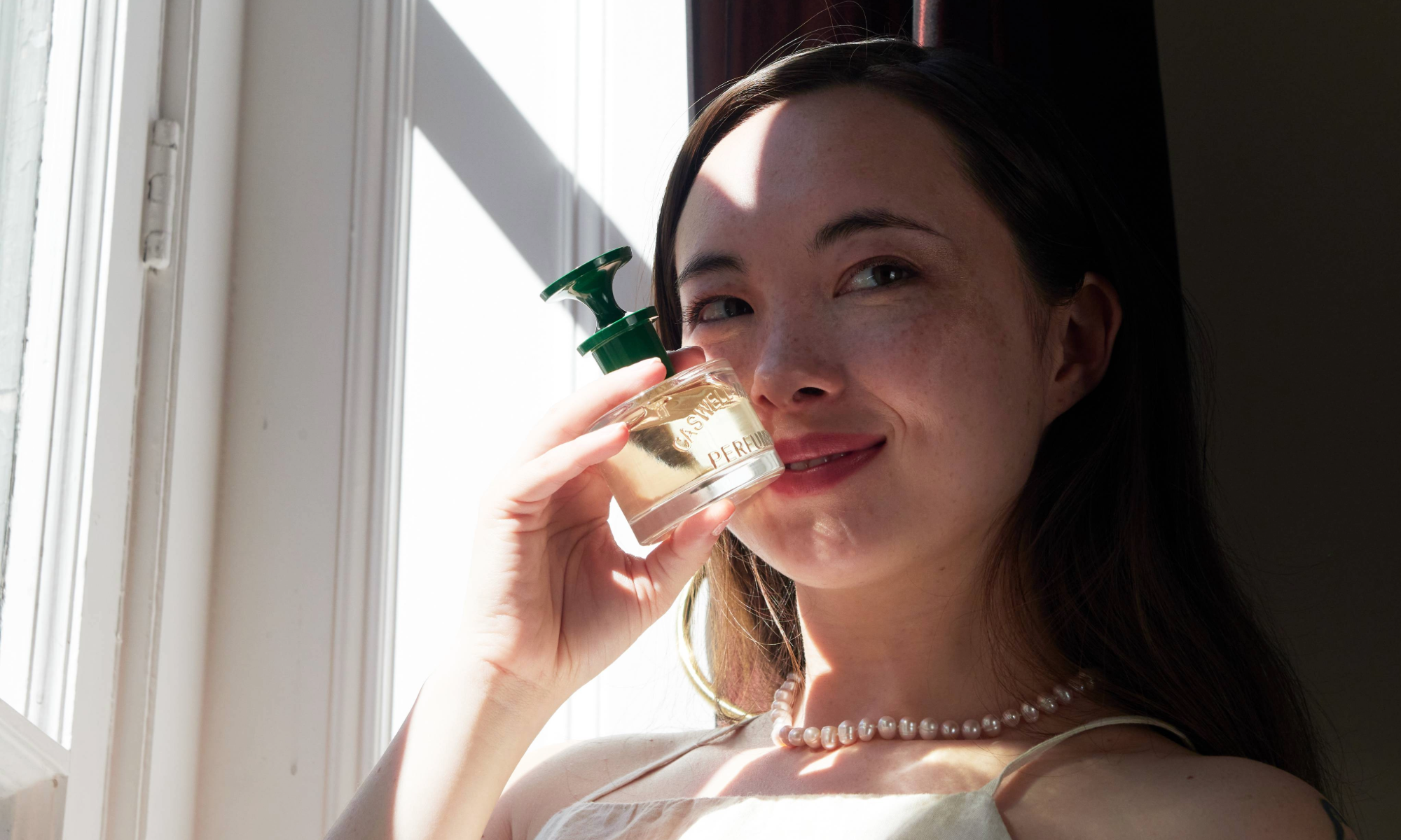 Caswell-Massey: Woman holding up bottle of perfume to face