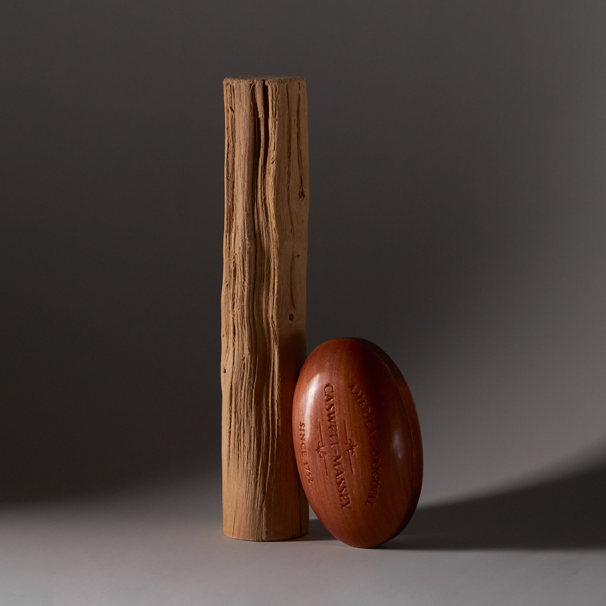 Woodgrain Sandalwood Bar Soap leaning against a piece of Australian sandalwood