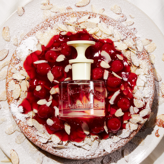 a cherry pie with a bottle of perfume on top