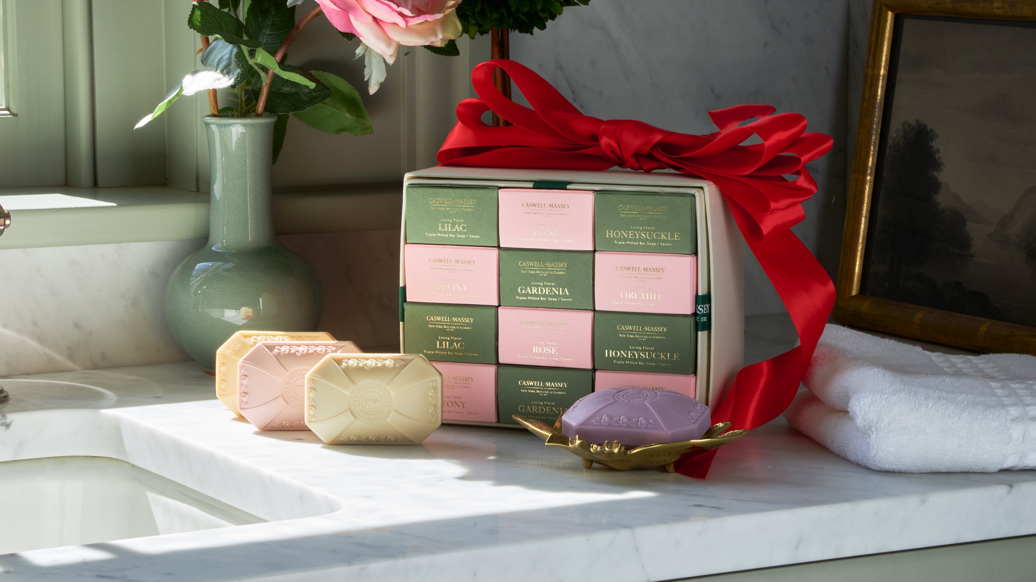 Caswell-Massey Designer Floral 12 Soap Gift Set wrapped in red ribbon with soft pastel colored decorative soaps on marble counter