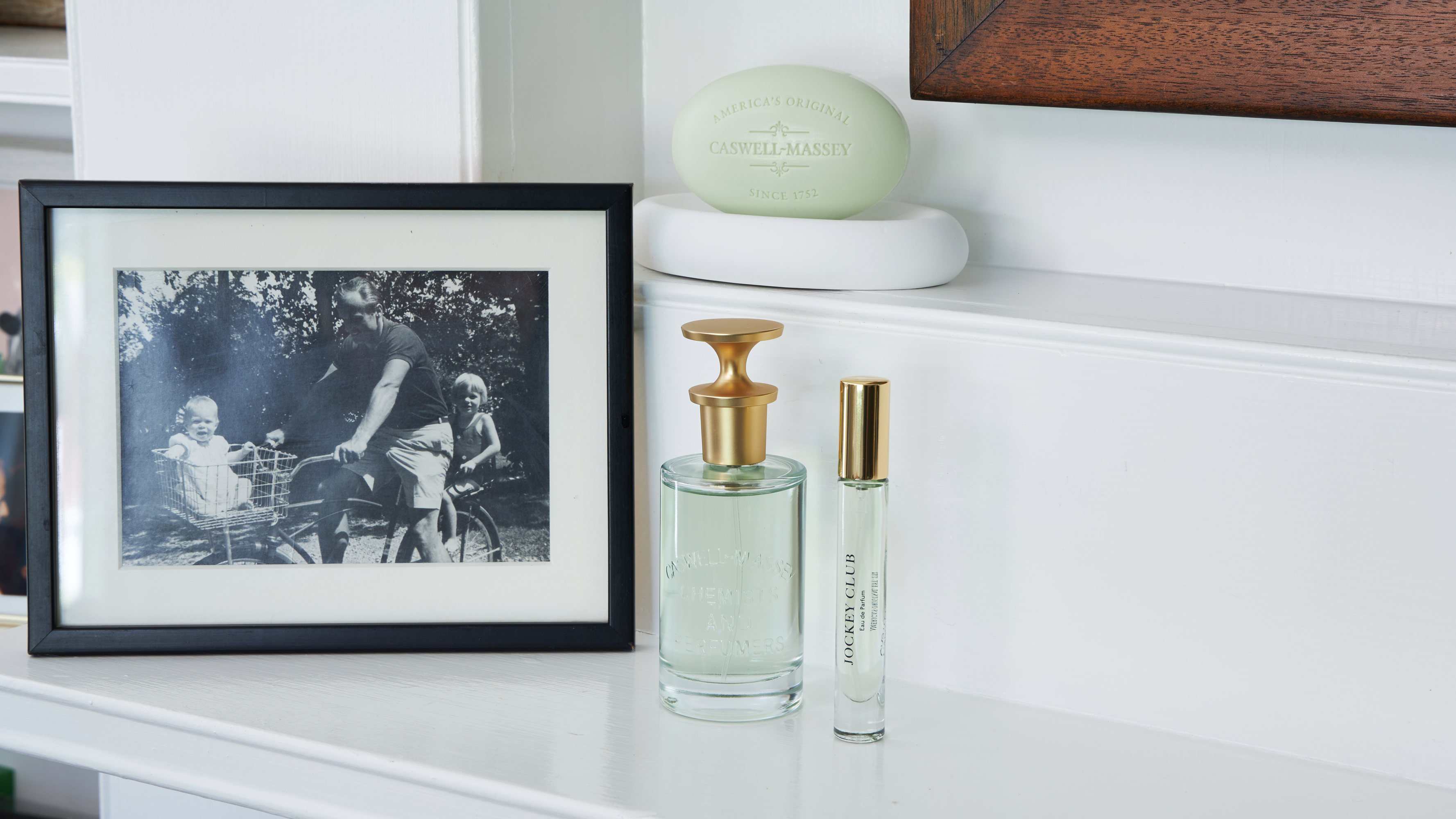 Caswell-Massey Jockey Club fragrance and soap sitting on a white mantle next to a family photo