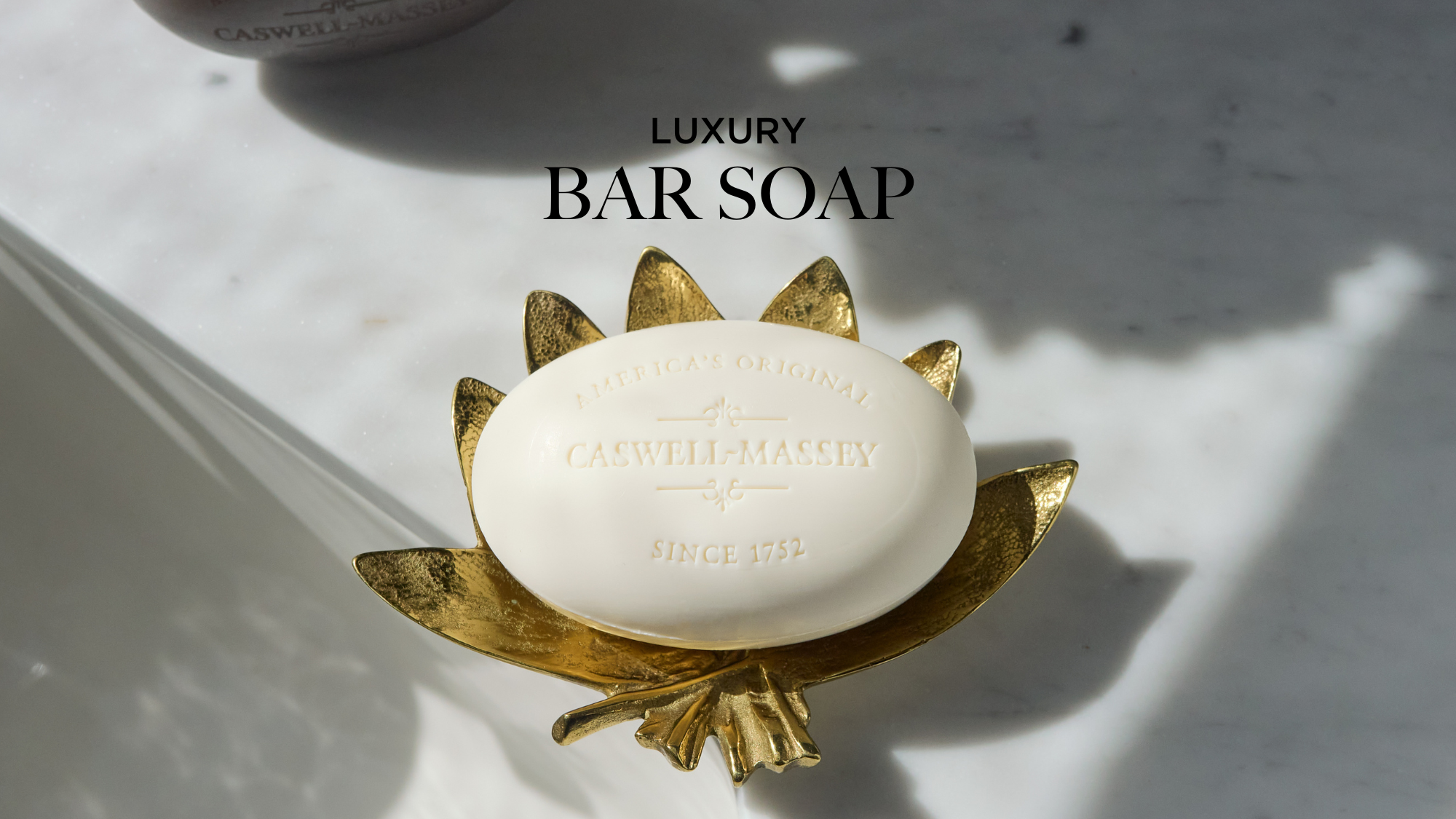Caswell-Massey Luxury Almond Bar Soap: White oval bar soap shown sitting on antique brass soap dish