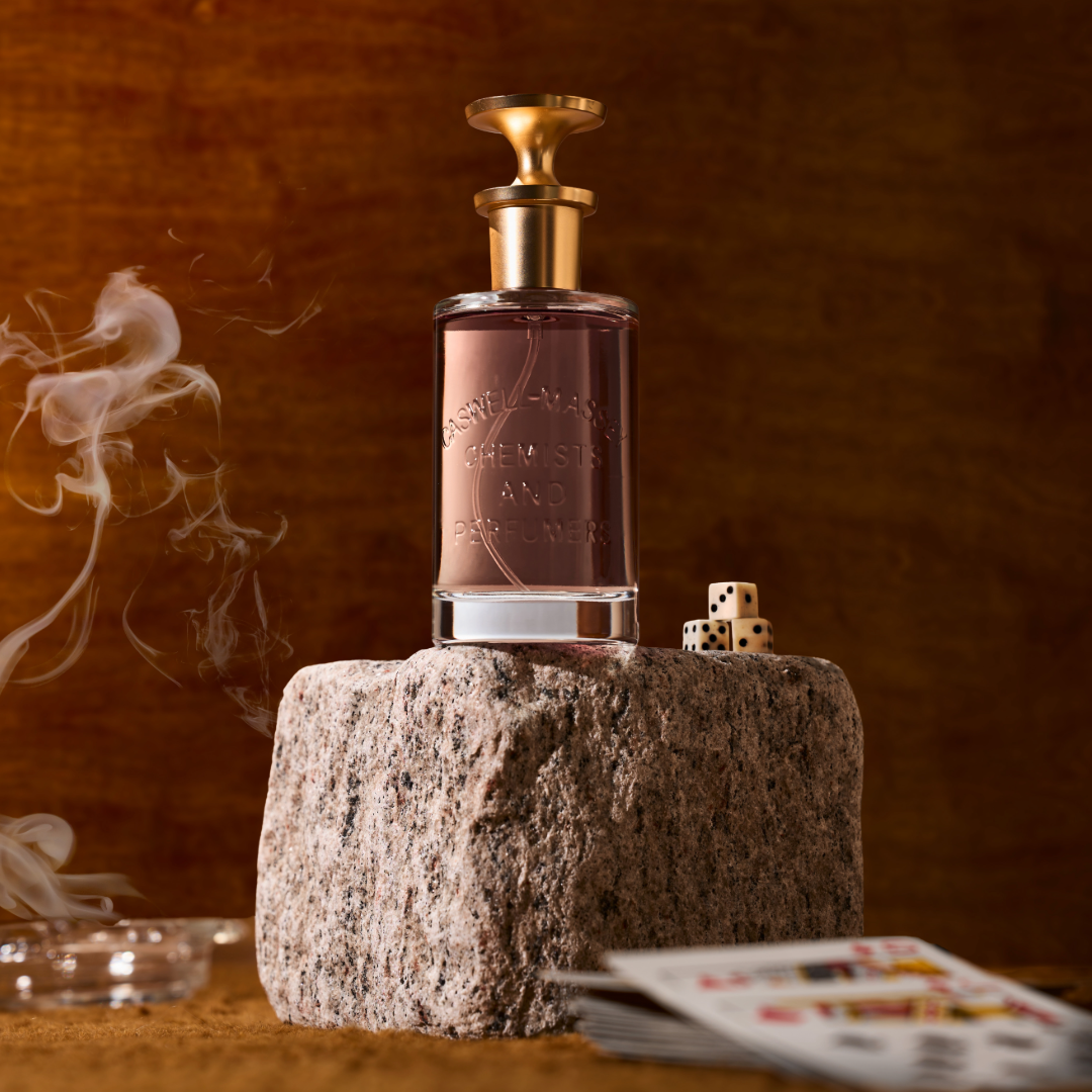 Caswell-Massey LX48 Eau de Parfum: bottle on a stone block with smoke and playing cards in the background