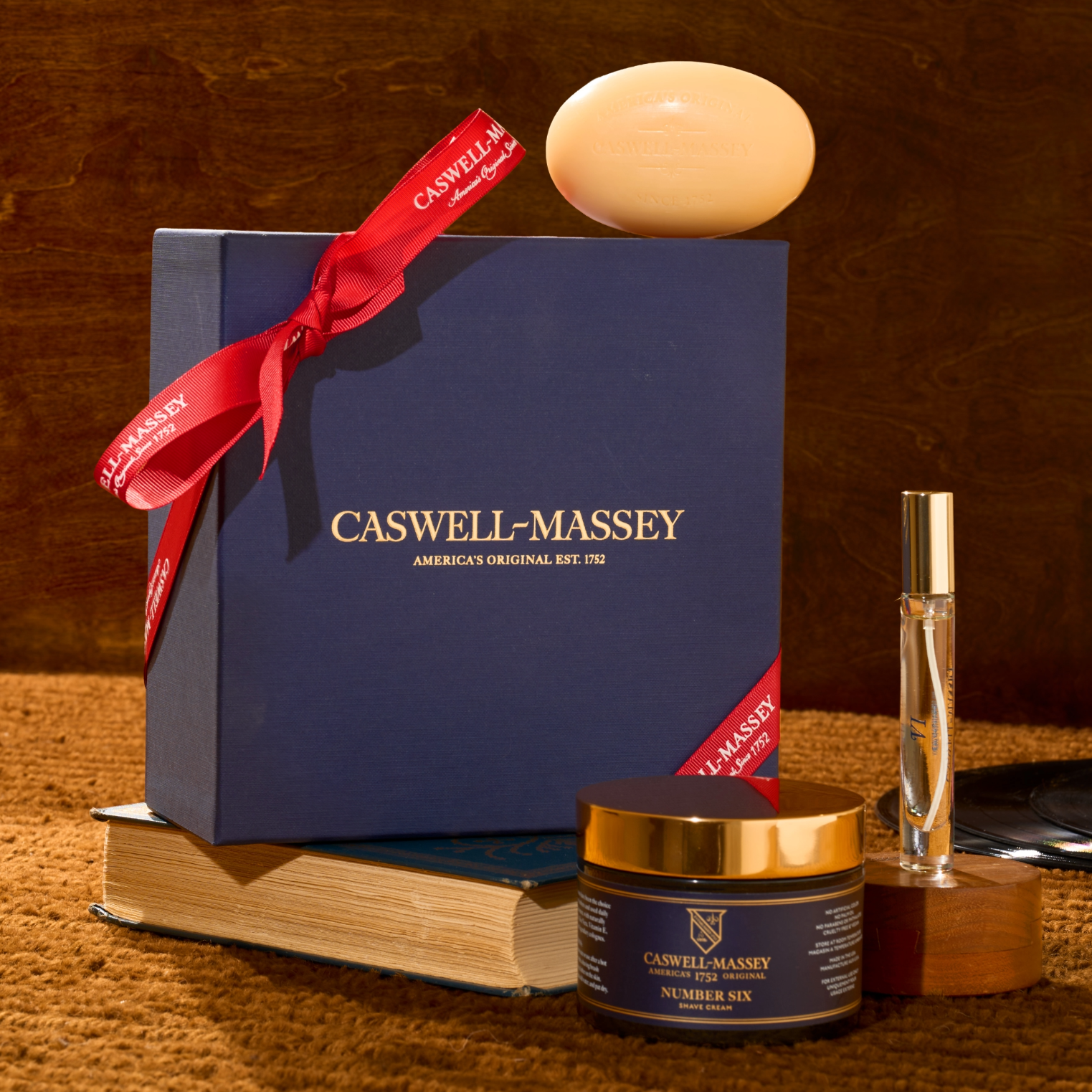 Caswell-Massey Number Six Shave Gift Set including a blue box, Number Six Bar Soap, Number Six Eau de Parfum 7.5ml, and Number Six Shave Cream on a textured surface.