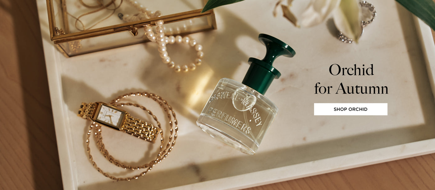 a bottle of perfume next to a necklace and a gold watch