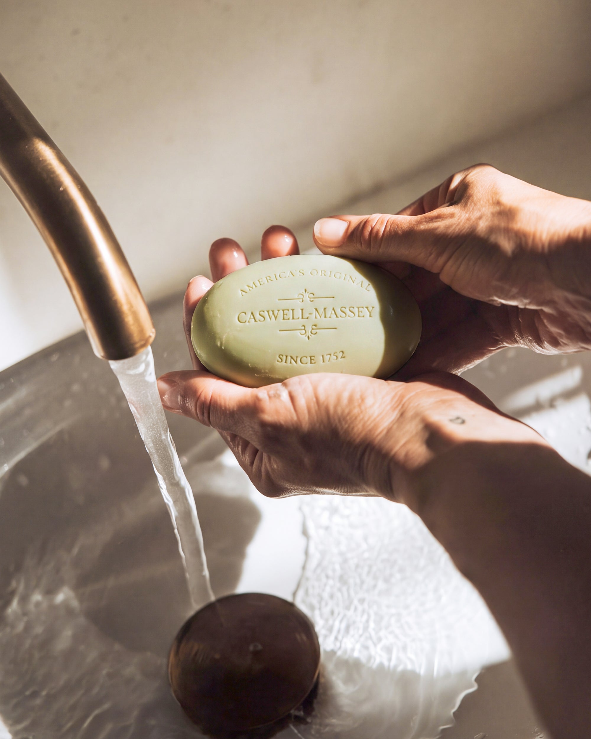 Man washing his hands using Caswell-Massey's RÒS Bar Soap at the sink.
