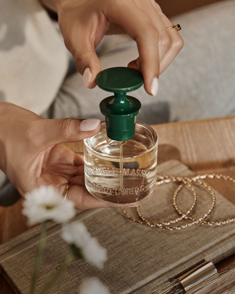 a person pouring a bottle of perfume
